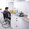 A man in a wheelchair doing the dishes.