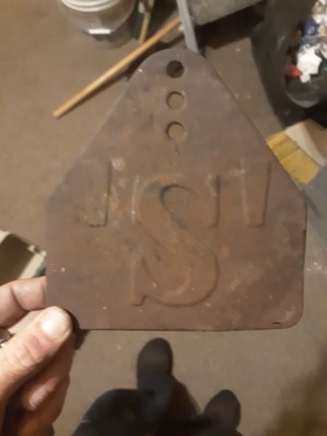 A rusty metal plate with the letter 'S' in the center.