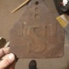 A rusty metal plate with the letter 'S' in the center.