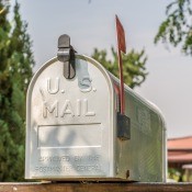 A metal mailbox in front of a house.