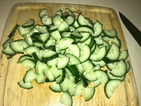 Chopped cucumbers on a wooden cutting board.