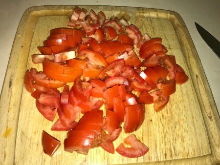 Chopped tomatoes on a wooden cutting board.