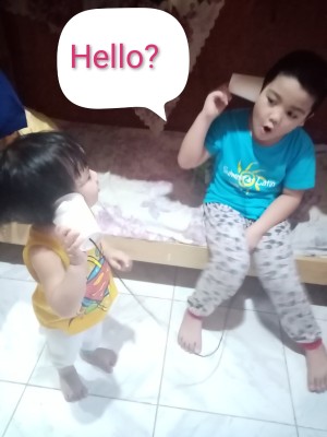 Paper Cup and String Telephone - two young children talking on the phone