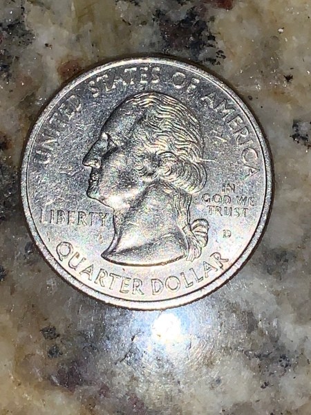 A U.S. quarter on a marble countertop.