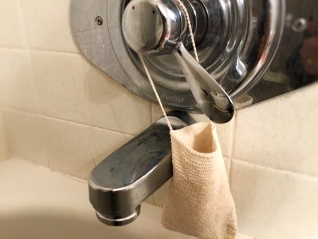 Crocheted Exfoliating Soap Sack - bag hanging on water temp knob in shower