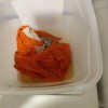 A container of fabric rags in a sanitizing solution.