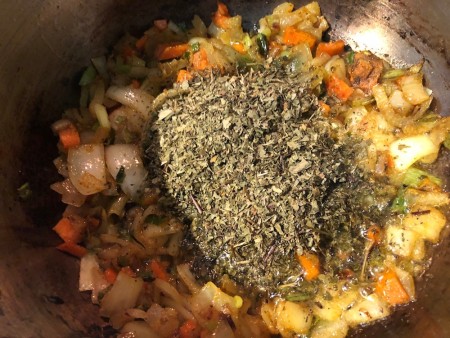 herbs added to veggies in pan