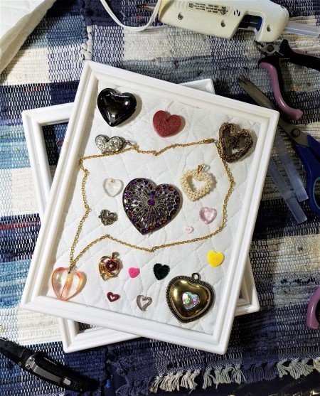 Protecting and Displaying Your Collection - hearts arranged on quilted fabric inside the frame