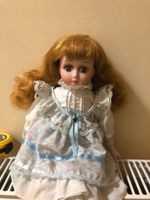 Identifying a Porcelain Doll - doll wearing a white dress trimmed with lace and blue ribbon