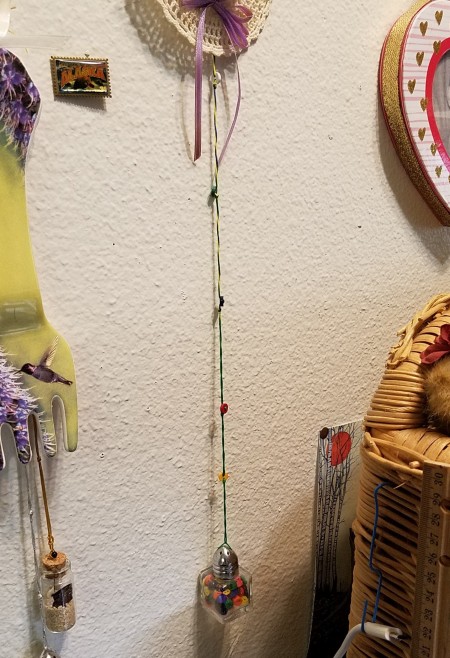 Two decorative glass bottles hanging below artwork.