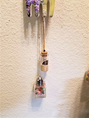 Two decorative glass bottles hanging below artwork.