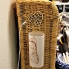 Eyeglasses hanging on a plastic container attached to the side of a small wicker shelf.