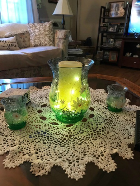 A flameless candle inside a green flowered vase.