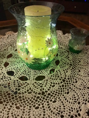 A flameless candle inside a green flowered vase.