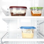 Labeled plastic containers of leftovers in the refrigerator.