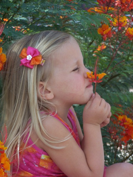 A girl smelling a colorful flower.