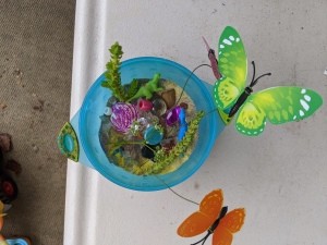 A small sand terrarium with butterflies around.