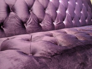 A couch upholstered in purple velvet.