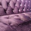 A couch upholstered in purple velvet.