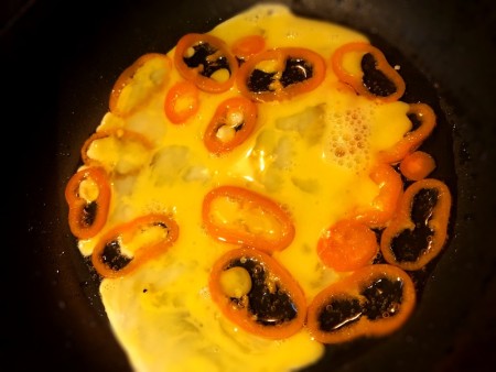 beaten egg poured on peppers