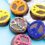 Chocolate coated sandwich cookies with sprinkles in the shape of a peace sign.