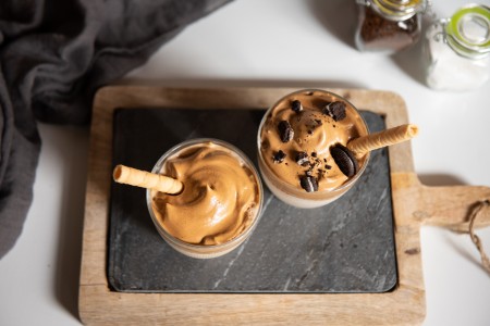 Dalgona in a cup on a cutting board.