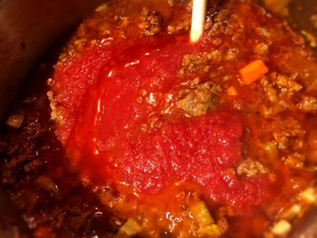 adding tomato sauce and broth to sauce