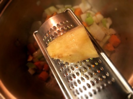Shredding fresh ginger into the soup pot.