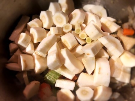 Adding chopped parsnips to the soup pot.
