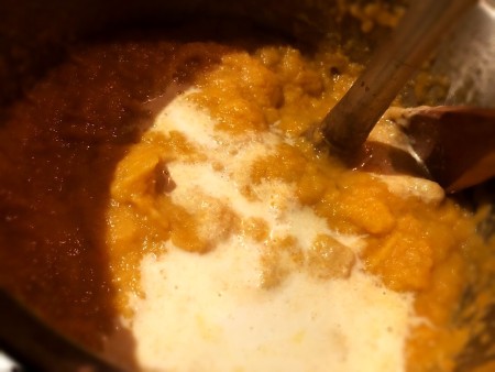 Adding milk to the soup pot.