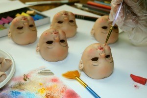 A collection of porcelain doll heads being painted.