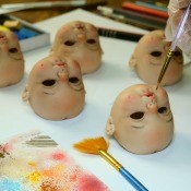 A collection of porcelain doll heads being painted.