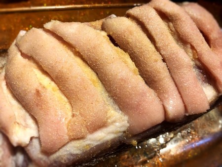 A pork roast cut with several slits.