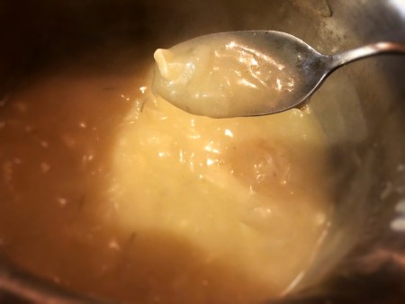 A spoon with the onion gravy mixture.