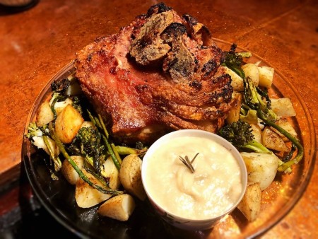 A plate of crispy pork roast with apple onion gravy.