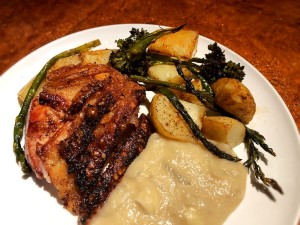 A plate of crispy pork roast with apple onion gravy & veggies.