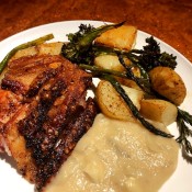 A plate of crispy pork roast with apple onion gravy & veggies.