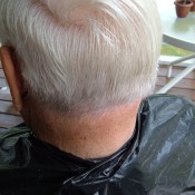 A trash bag being used as a cape for cutting hair.