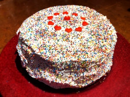 The strawberry ice cream cake decorated with hearts and sprinkles.