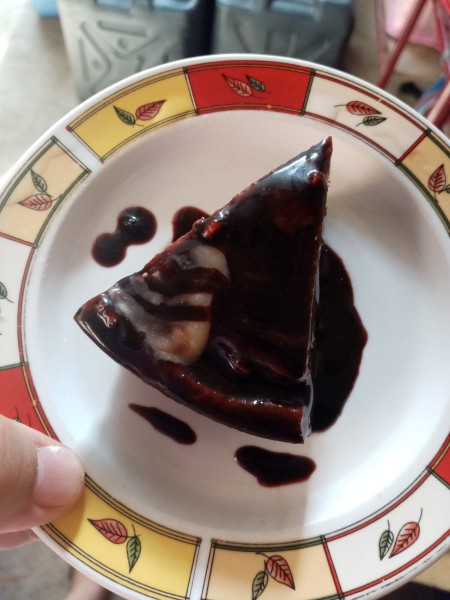 A piece of glazed custard chocolate cake.