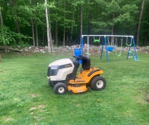 Battery Hooked Up Wrong on Cub Cadet - riding mower in large yard with swing set in background