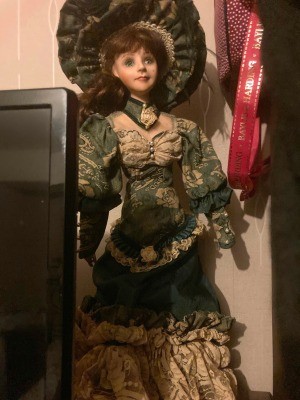 Identifying a Porcelain Musical Doll - doll with dark green and tan Victorian style dress and matching large hat, standing next to a computer monitor