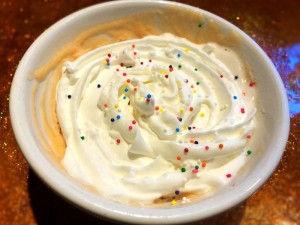 Finished mug cake topped with sprinkles and whipped cream.
