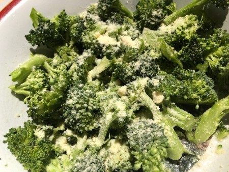 A bowl of broccoli pieces with Parmesan.