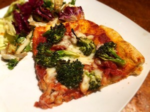 A slice of pizza with salad on plate
