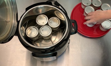 Adding canning jars filled with yogurt to an Instant Pot pressure cooker.