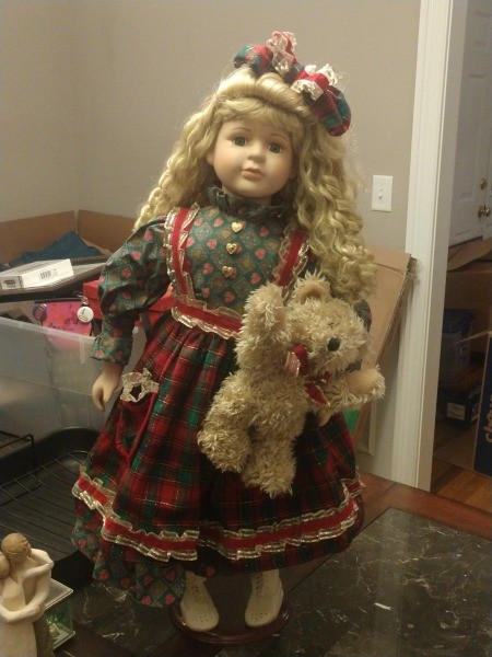 Value of a Collector's Choice Porcelain Doll? - doll wearing a print dress with a plaid apron and holding a teddy bear