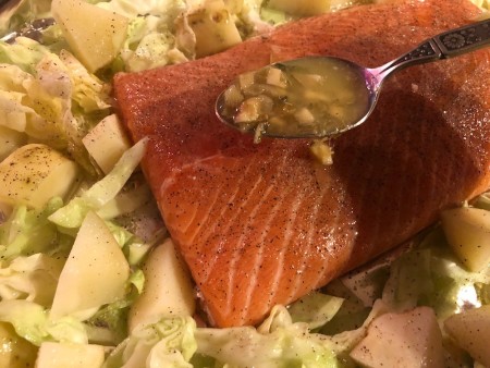 Spooning garlic butter mixture over salmon.