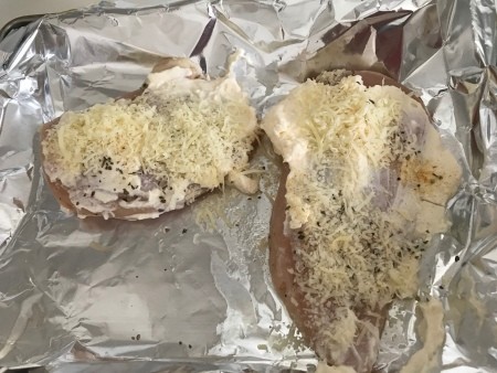 chicken breasts covered in mayo, parmesan cheese and spices.