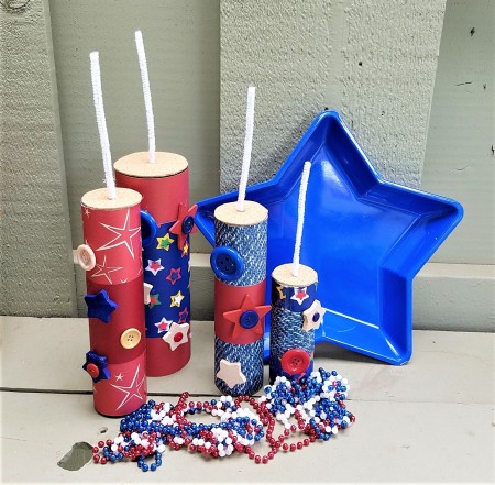 Faux Firecrackers - final display with plastic blue star bowl and red, white, and blue beads arrayed in front of the four firecrackers